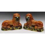 A pair of 19th century Staffordshire mantel lions, each with glass eyes and painted in tones of