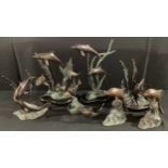 A set of seven bronze and bronzed dolphin groups, the tallest 28cm, in assorted swimming poses