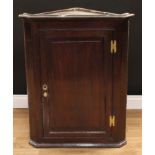 A George III oak wall hanging corner cabinet, moulded cornice above a raised and fielded panel