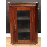 A mahogany corner display cabinet, moulded cornice above a glazed door enclosing two shelves,