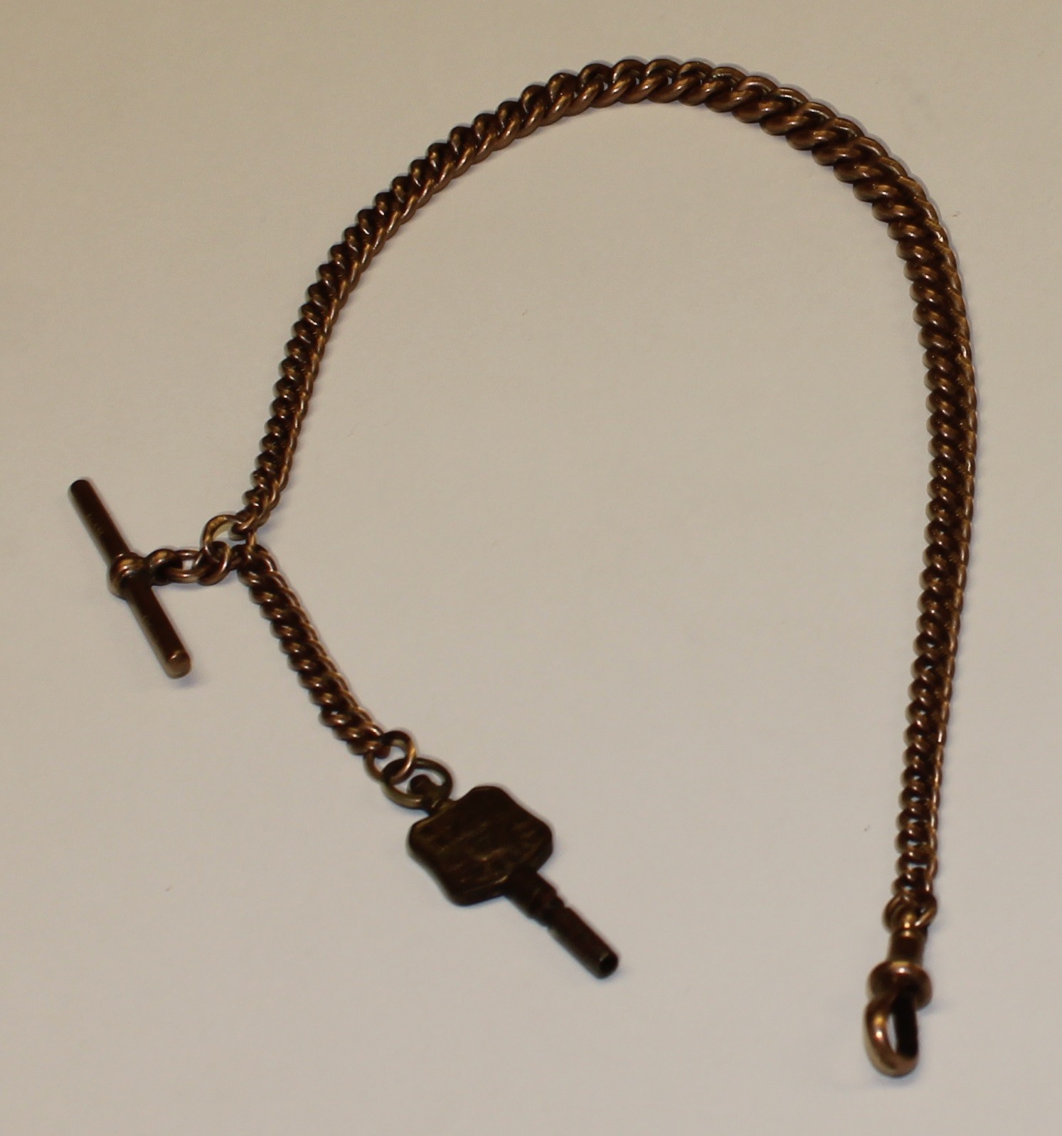 A 9ct rose gold Albert chain with 9ct rose gold t-bar, and a metal pocket watch key, 34g