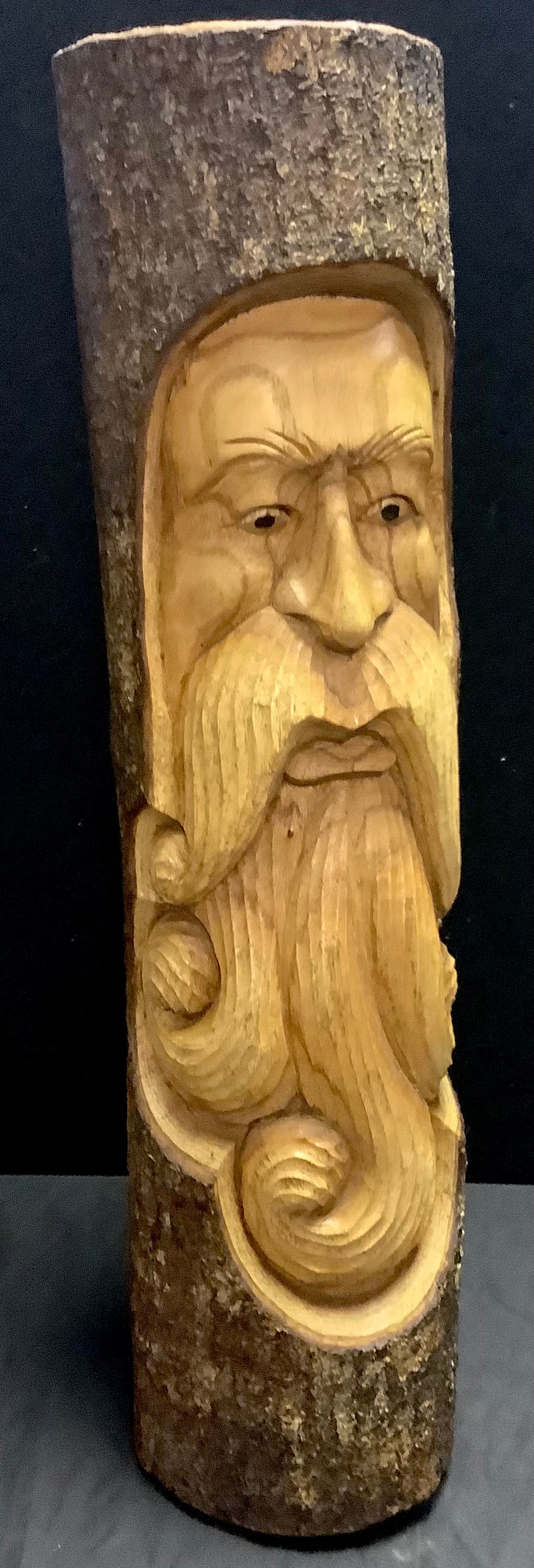 A carved wooden trunk section, applied with a Green Man type bearded gent in relief, 49cm