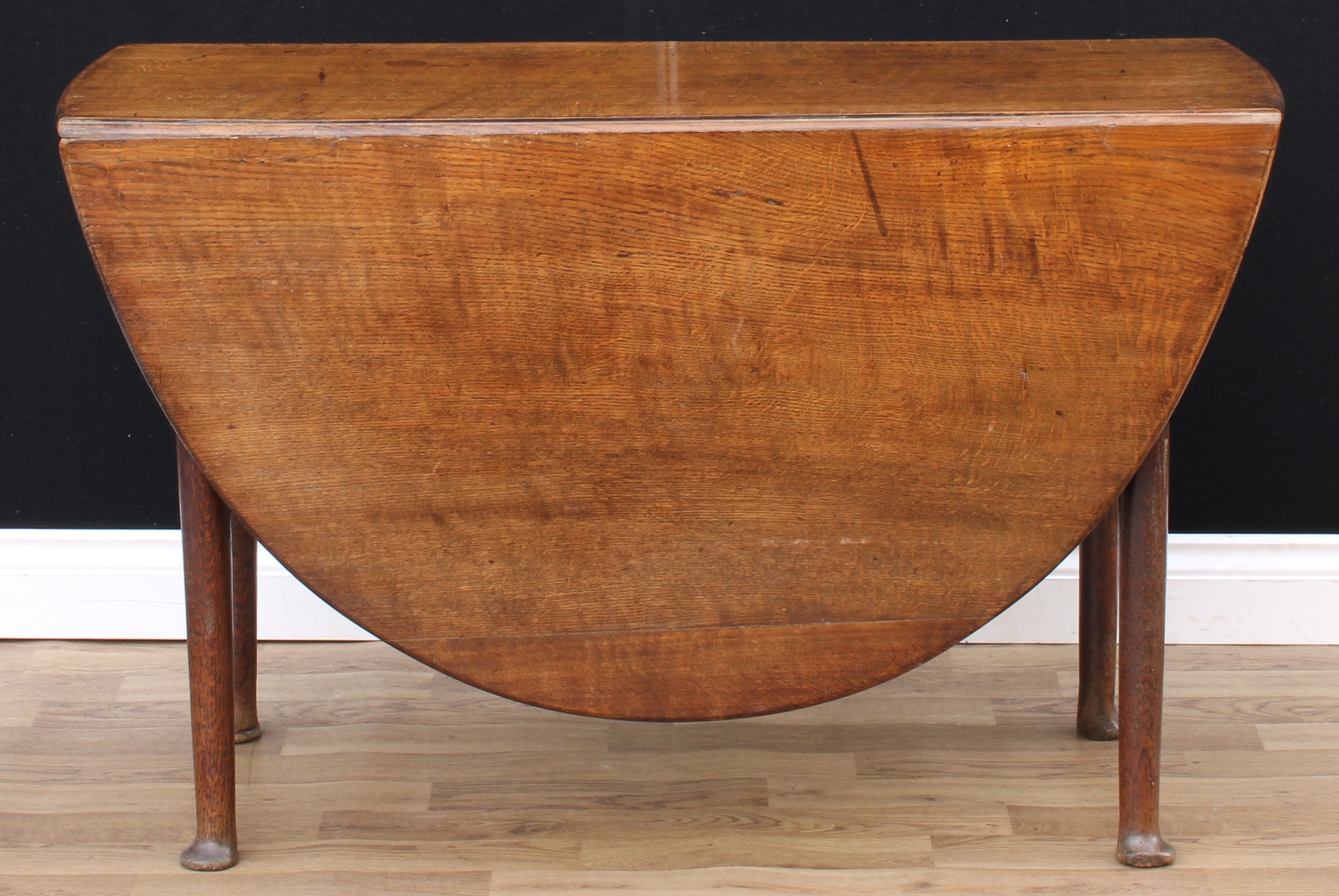 A 'George II' oak gateleg dining table, oval top with fall leaves, cylindrical legs, pad feet,