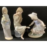 A Lladro figure, girl holding a bunch of lilies, 23cm high; a Nao by Lladro figure, young girl