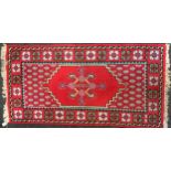 A 20th century Tunisian woolen runner, central geometric medallion within triple border, red ground,