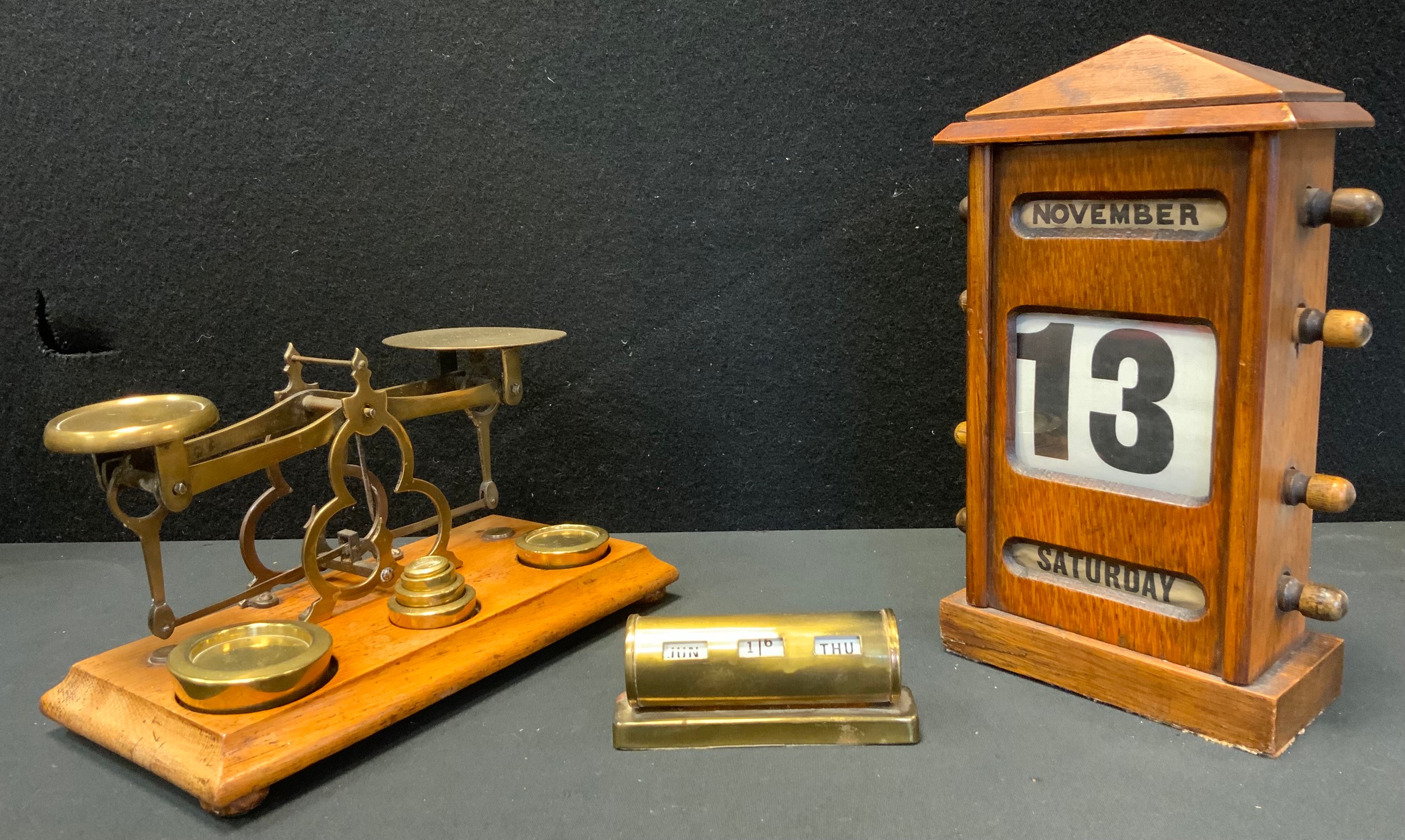An early 20th century oak perpetual desk calendar, above glazed apertures for day, date and month,