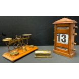 An early 20th century oak perpetual desk calendar, above glazed apertures for day, date and month,