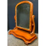 A Victorian mahogany dressing mirror, arched mirror, scroll supports, serpentine base.62cm high,