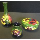 A Moorcroft pottery Hibiscus pattern circular trinket bowl and cover; similar vase; another