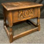 A 20th century oak stool, hinged top, the front carved with mask and scrolls, 52cm wide, c.1920