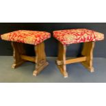 A pair of heraldic upholstered oak foot stools, shaped legs, pegged bar stretcher, 45cm high, 44cm