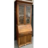 An Arts & Crafts oak bureau bookcase, outswept cornice above a pair of astragal cupboard doors