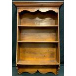 A 20th century oak wall hanging display shelves, outswept cornice above three shelfs. 115cm high,