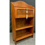 An Arts and Crafts period oak bookcase cabinet of small proportions, arched pediment, small drop