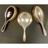 A George V silver hand mirror, Chester 1912; similar brush, Birmingham 1911 etc (3)