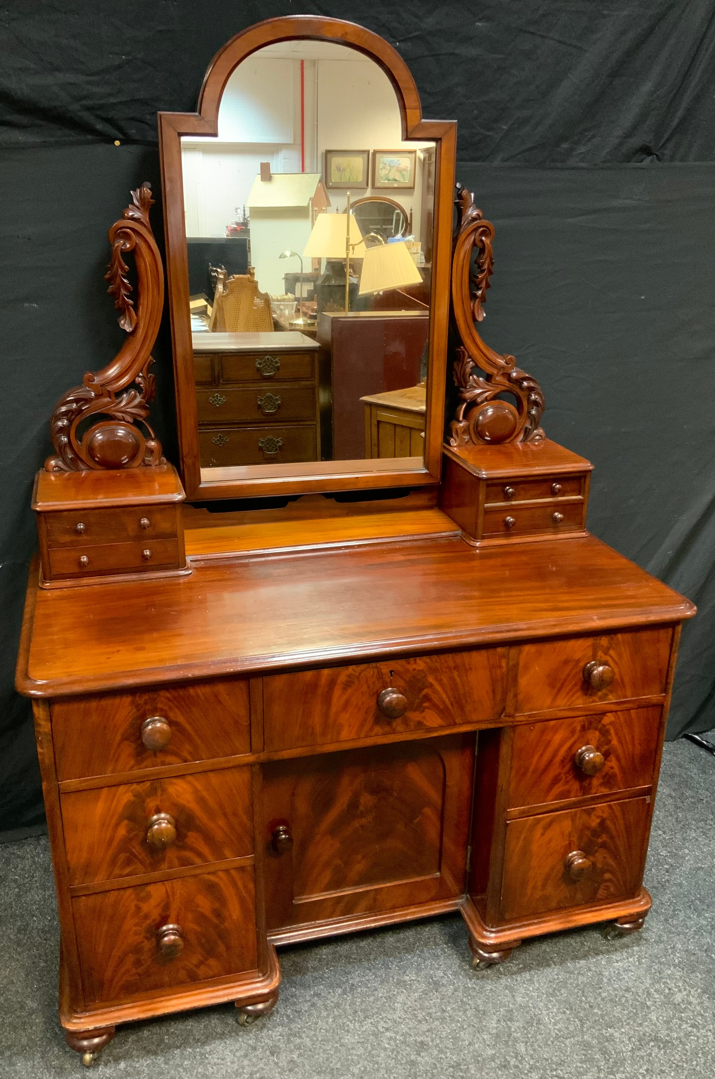 A Victorian Mahogany Dressing Table, the arch-top mirror on carved supports, flanked by two pairs of