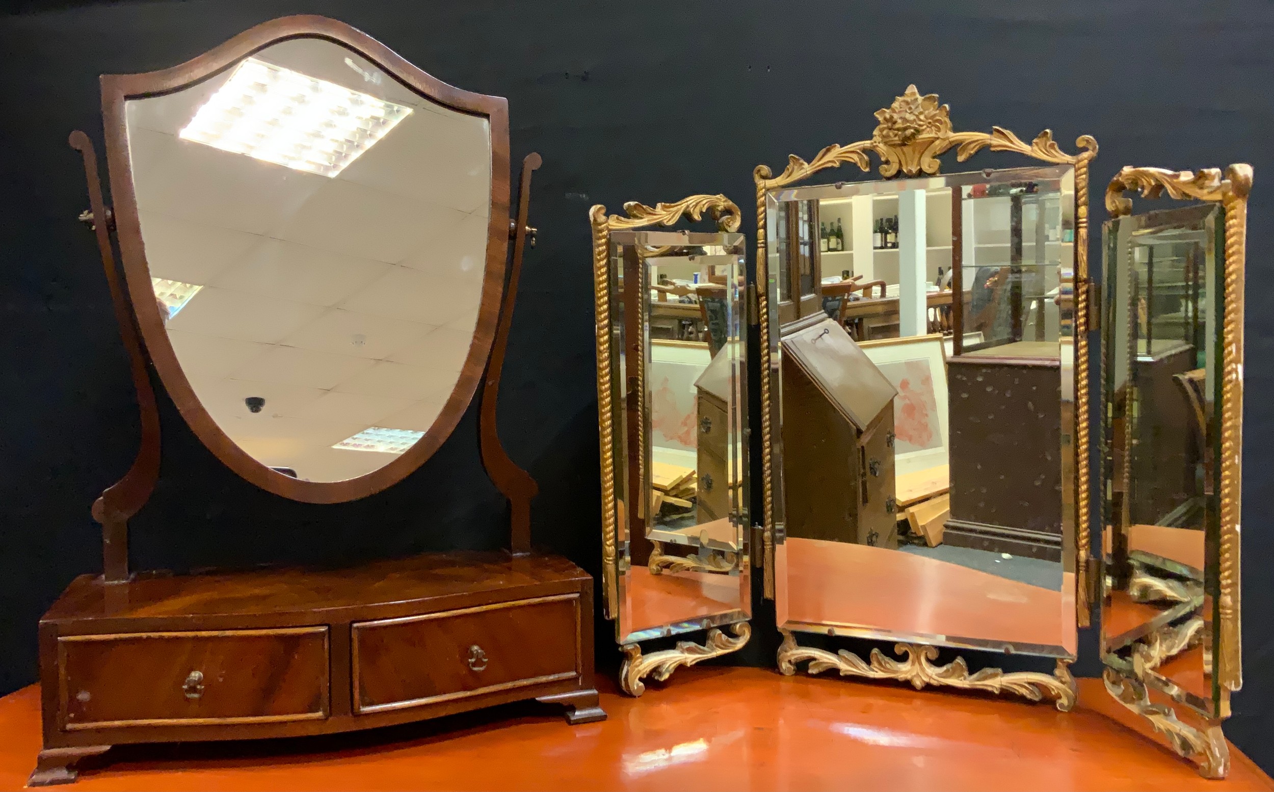 A 20th century, George III style mahogany veneered Toilet Mirror, the shield-shaped mirror on gently