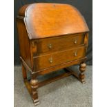 A 20th century oak bureau, arched top, fall front above two long drawers, turned and carved