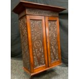 A 19th century wall hanging oak cupboard, outswept cornice above a pair of carved cupboard doors