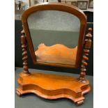 A Victorian mahogany arched mirror, turned supports, serpentine shaped base, 65cm high, 6cm wide,