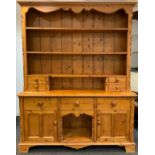 An Early 20th Century Country Kitchen Pine Dresser, having a shaped pediment, over three tiers of