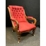 A late Victorian fireside arm chair, button back, scrolled arms, turned legs, ceramic casters, c1890