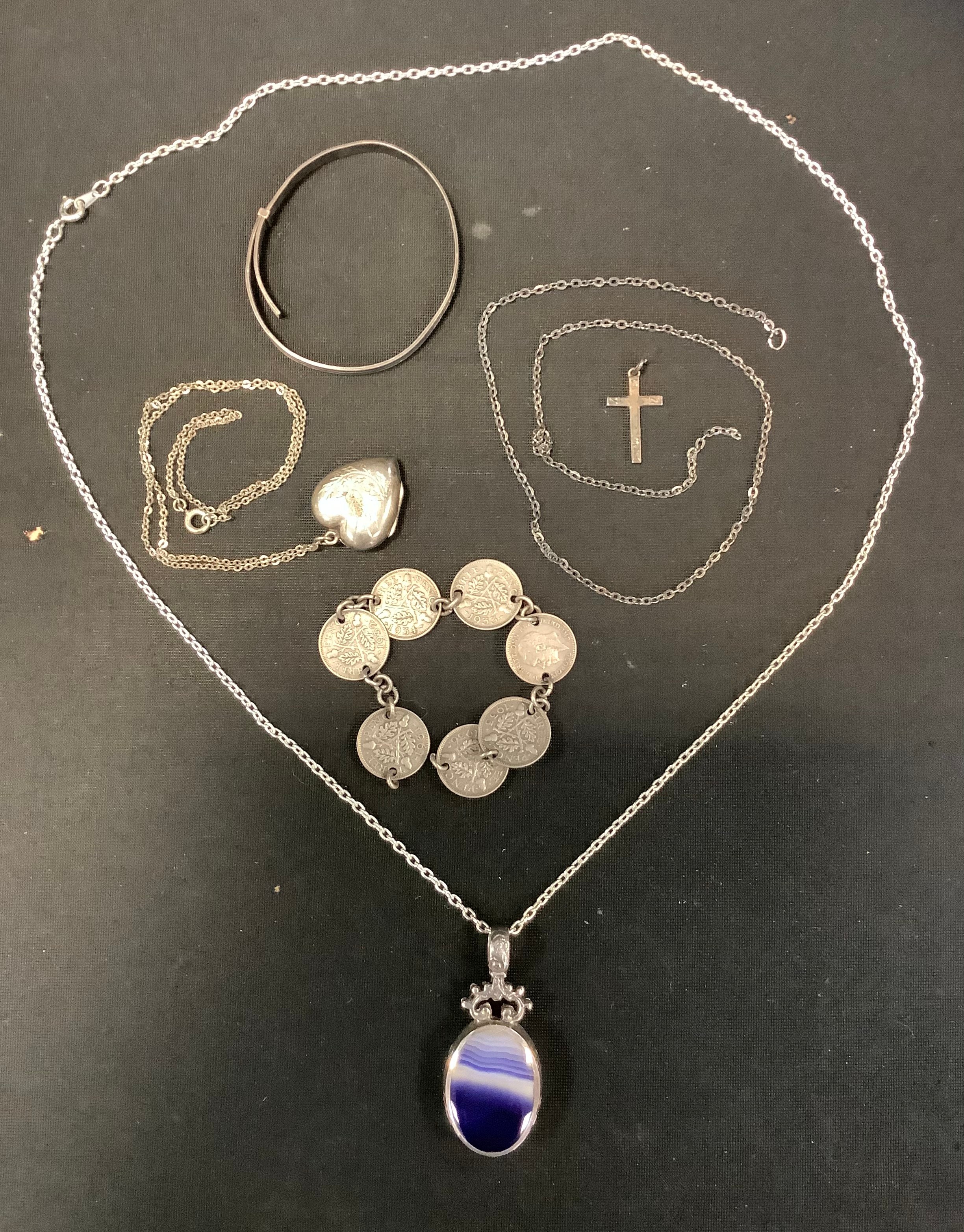 A silver mounted oval pendant, set with an amethyst; a silver heart locket; silver child's bangle;