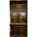 A Victorian mahogany bookcase, outswept cornice about a pair of glazed panel doors enclosing