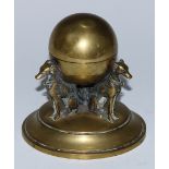 A 19th century brass inkwell, as a sphere supported by three seated dogs, hinged cover, circular