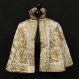A 19th century evening or opera cape, richly embroidered in gold thread with meandering foliate