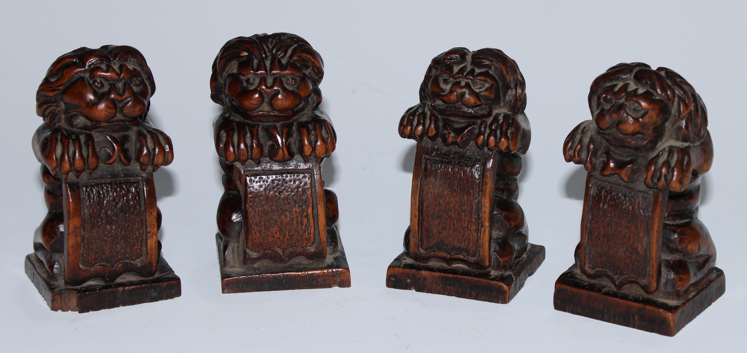 A set of four Baroque walnut carvings, as kneeling anthropomorphic lions with shields, 8.5cm high,