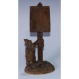 A Black Forest novelty country house menu stand, carved as a gnome holding a lantern beneath a