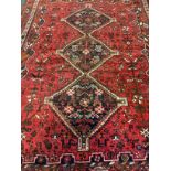 An early to mid 20th century Persian Shiraz wool rug, hand-knotted in deep red, the central field
