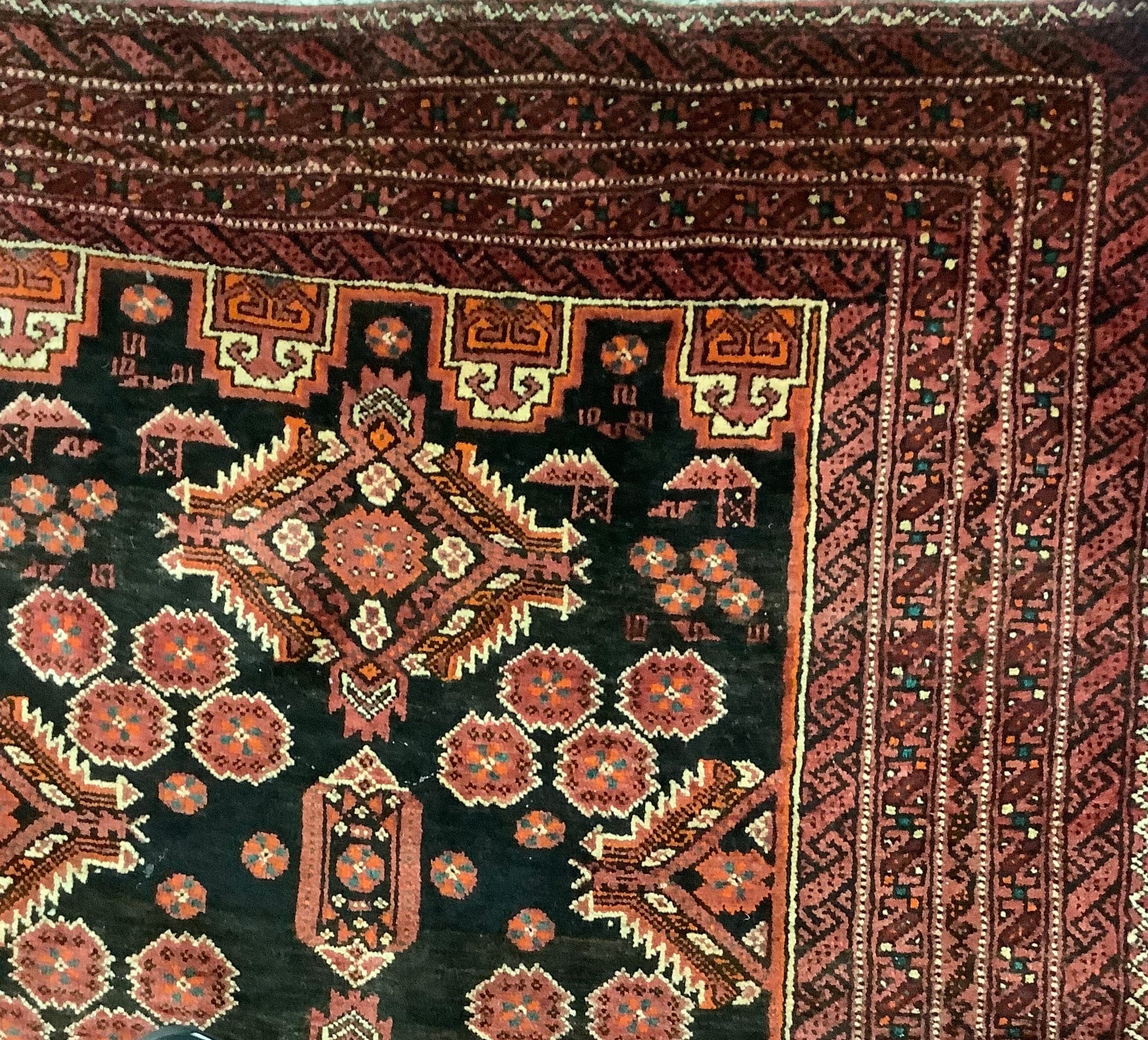 A Baluchi carpet in rich tones of black and claret, triple pole medallions, surrounded by - Image 2 of 3