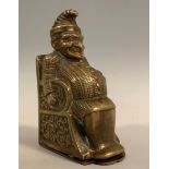 A novelty brass vesta case, as Mr Punch, seated in a chair, hinged striker base, 6cm high, c.1900.