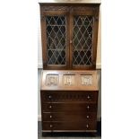 A mid 20th century oak bureau bookcase of small proportions, the small moulded cornice over a carved