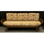 An Ercol Studio range Elm daybed sofa, shaped panel back, with original patterned seat cushion ( the