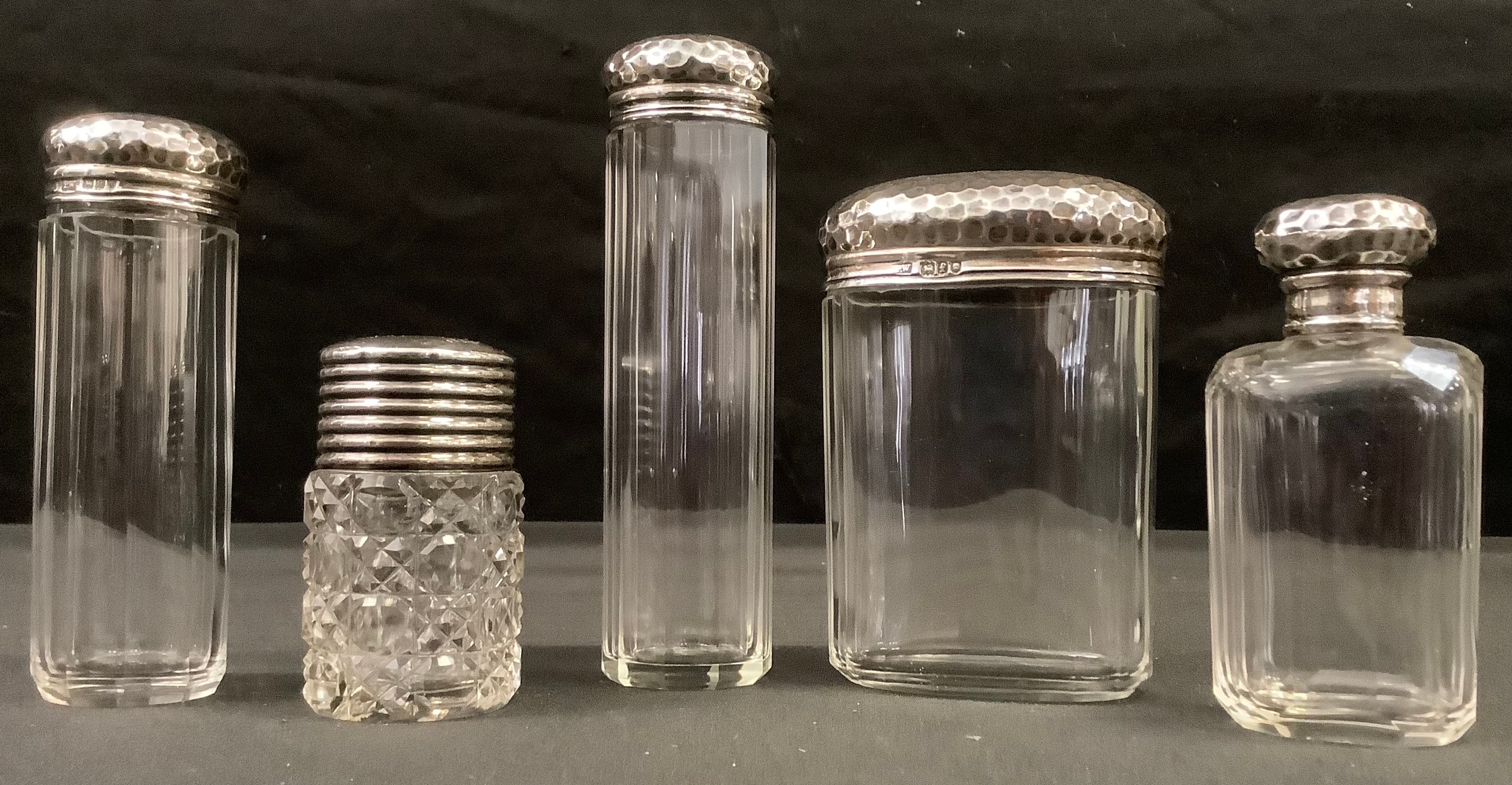 A set of four George V silver dressing table bottles, hammered covers, London 1901; another late