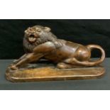 A 19th century native folk art carving of a lion, seated with front paws outstretched, rounded base,