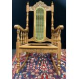 A 20th century pine rocking chair, carved cresting, cane back, turned supports, 110cm high.