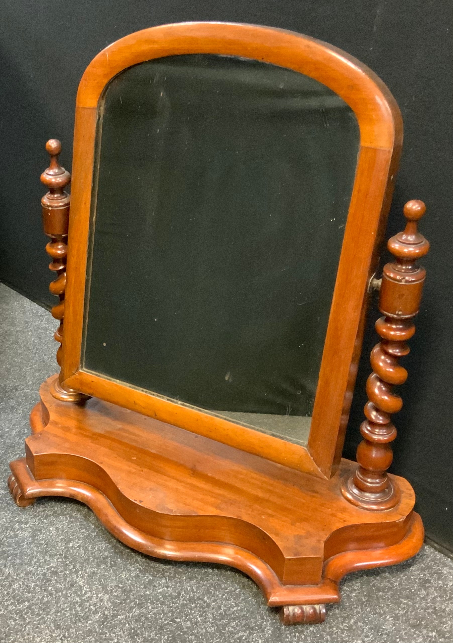 A Victorian mahogany arched mirror, turned supports, serpentine shaped base, 65cm high, 6cm wide,