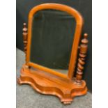 A Victorian mahogany arched mirror, turned supports, serpentine shaped base, 65cm high, 6cm wide,