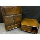An Ercol dark Elm side cabinet, fall front top, above pair of panel doors and single drawer,