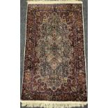 A Persian Kashan type carpet, finely woven with an intricate central field, in red, green, and blue,