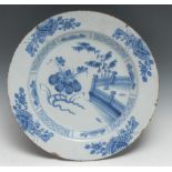 An English 18th century Delft charger, decorated in underlaze blue with stylised flowers and