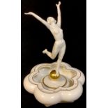 A Hutschenreuther figure, modelled by K Tutter, dancing female nude with golden orb, within a flower