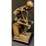 A contemporary bronzed resin sculpture, 'The Thinker' modelled as a skeleton, 50cm high