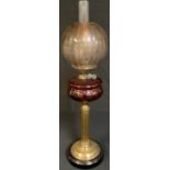 A Victorian brass columnar oil lamp, cranberry glass font, etched glass shade, 75cm high over