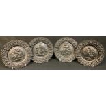 A set of four cast iron plates, each in relief with classical figures, 20.5cm diam