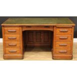 An early-mid 20th century oak desk, rounded rectangular top with writing surface, above a pair of